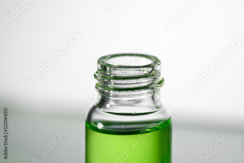 Opened glass bottle with transparent fluid hyaluronic acid, retinol, oil or serum on grey background. Cosmetics, science and healthcare concept closeup. Front view. Beauty product presentation, macro