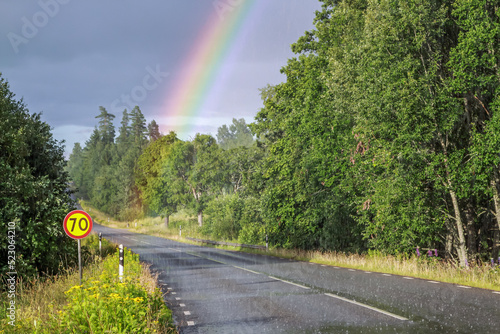 Empty Swedish road in the rain with a rainbow photo