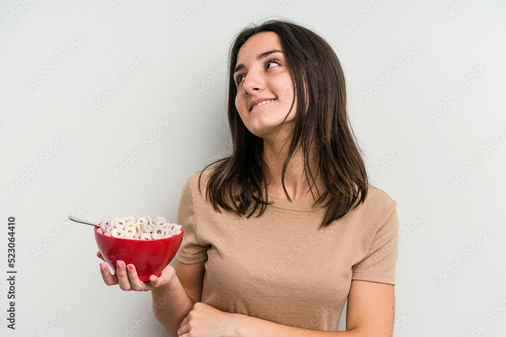 Young caucasian woman holding bowl of cereals isolated on white background laughing and having fun. Young caucasian woman holding bowl of cereals isolated on white background laughing and having fun.