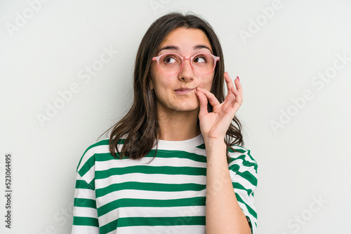 Young caucasian woman wearing a glasses isolated on blue background with fingers on lips keeping a secret.