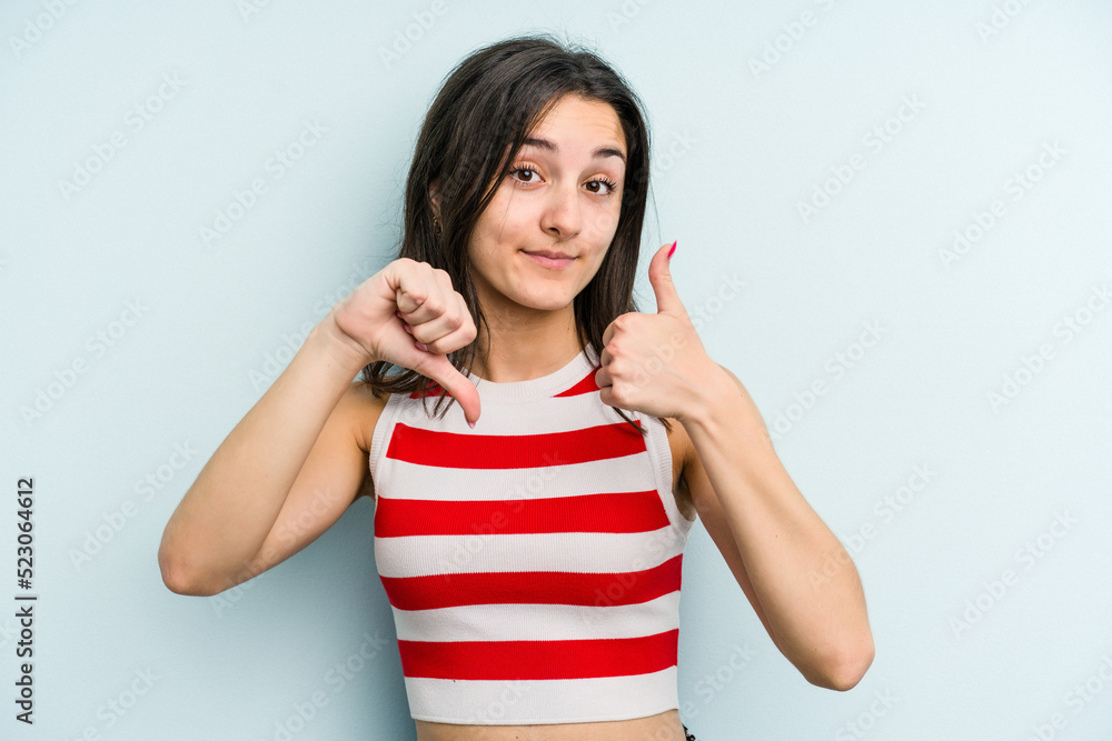Young caucasian woman isolated on blue background showing thumbs up and thumbs down, difficult choose concept Young caucasian woman isolated on blue background showing thumbs up and thumbs down, difficult choose concept