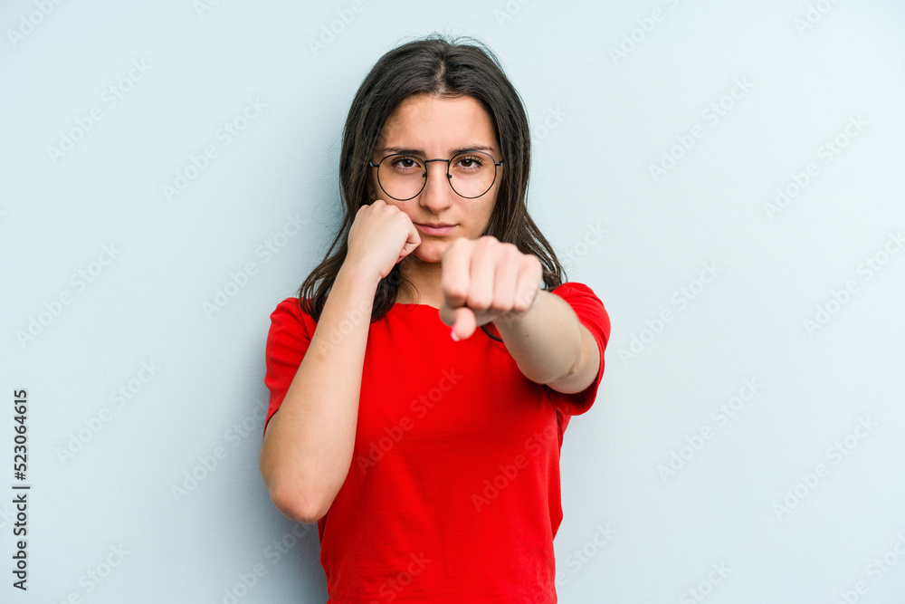 Young caucasian woman isolated on blue background throwing a punch, anger, fighting due to an argument, boxing. Young caucasian woman isolated on blue background throwing a punch, anger, fighting due to an argument, boxing.