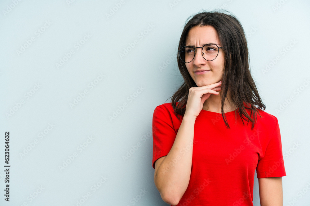 Young caucasian woman isolated on blue background touching back of head, thinking and making a choice. Young caucasian woman isolated on blue background touching back of head, thinking and making a choice.