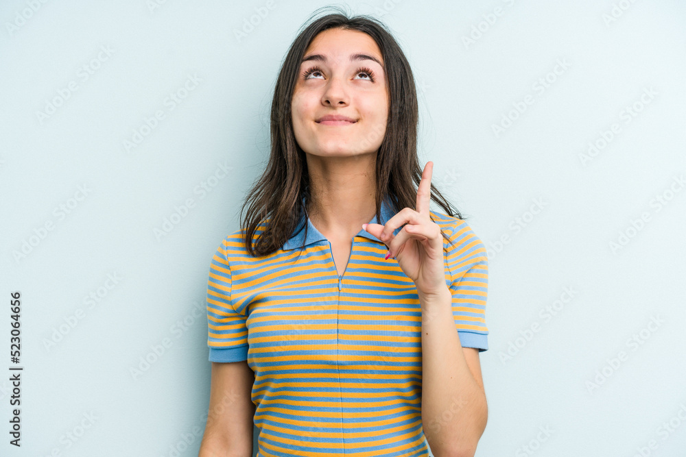 Young caucasian woman isolated on blue background indicates with both fore fingers up showing a blank space. Young caucasian woman isolated on blue background indicates with both fore fingers up showing a blank space.
