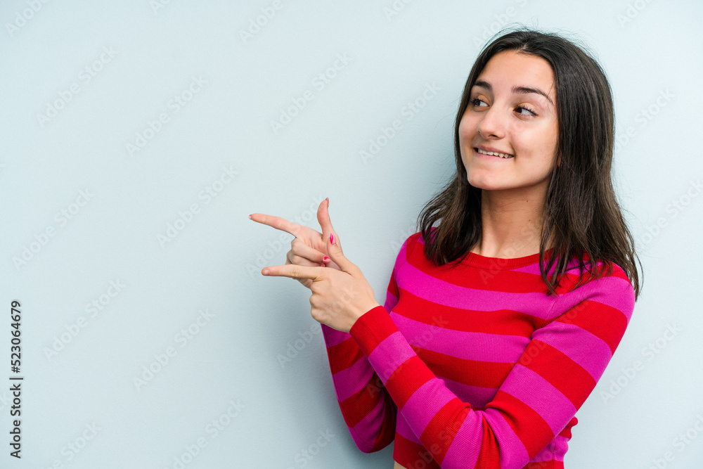 Young caucasian woman isolated on blue background points with thumb finger away, laughing and carefree. Young caucasian woman isolated on blue background points with thumb finger away, laughing and carefree.
