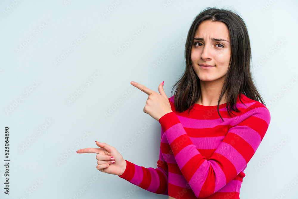 Young caucasian woman isolated on blue background shocked pointing with index fingers to a copy space. Young caucasian woman isolated on blue background shocked pointing with index fingers to a copy space.