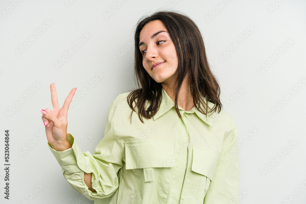 Young caucasian woman isolated on white background joyful and carefree showing a peace symbol with fingers. Young caucasian woman isolated on white background joyful and carefree showing a peace symbol with fingers.
