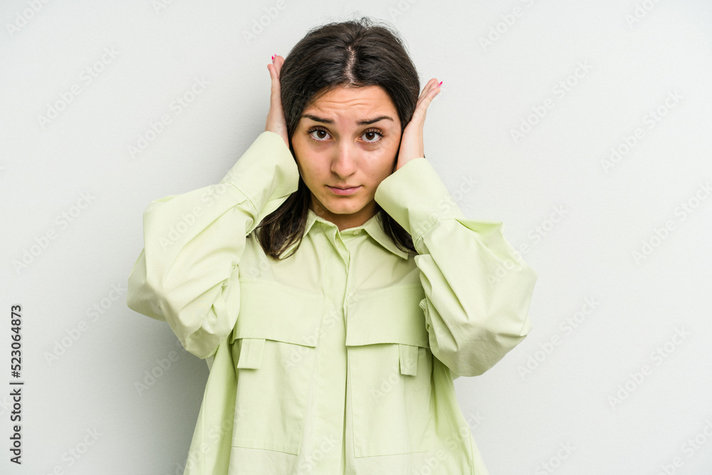 Young caucasian woman isolated on white background covering ears with hands trying not to hear too loud sound. Young caucasian woman isolated on white background covering ears with hands trying not to hear too loud sound.