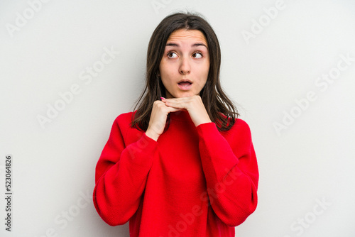 Young caucasian woman isolated on white background praying for luck, amazed and opening mouth looking to front.