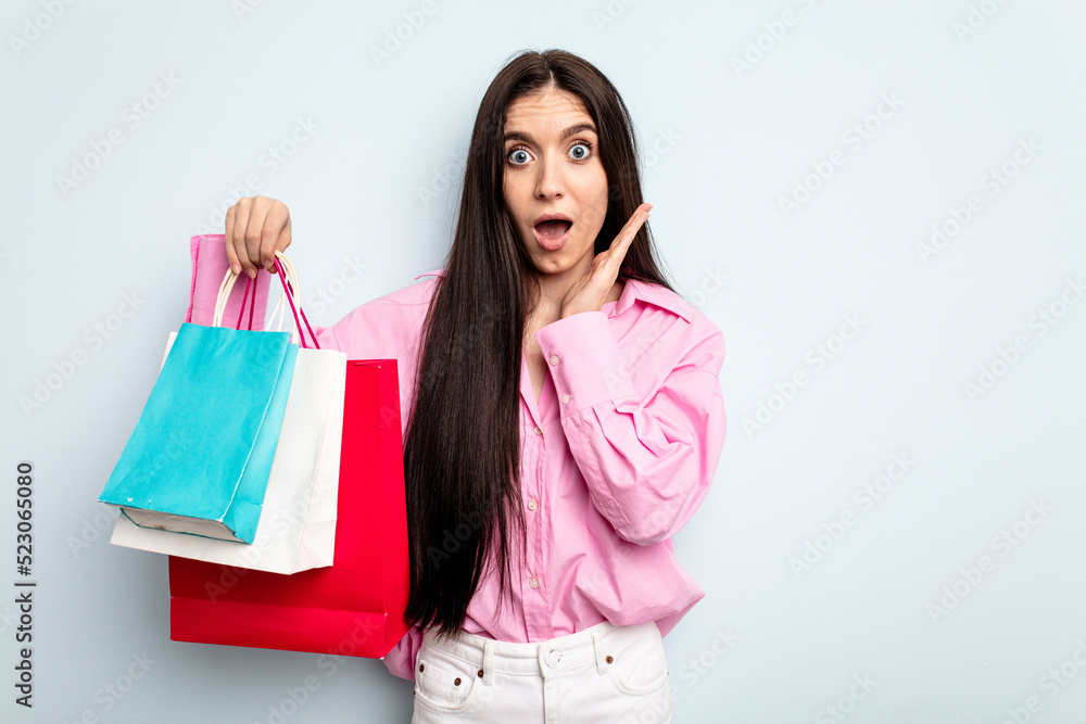 Young caucasian woman going to buy some clothes isolated on blue background surprised and shocked.