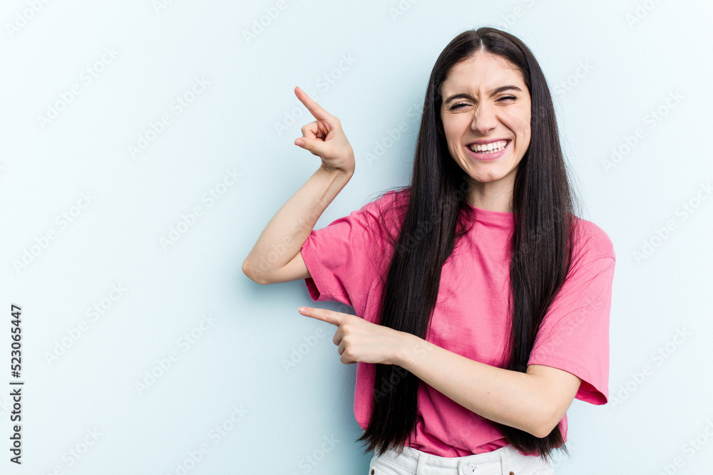 Young caucasian woman isolated on blue background excited pointing with forefingers away. Young caucasian woman isolated on blue background excited pointing with forefingers away.