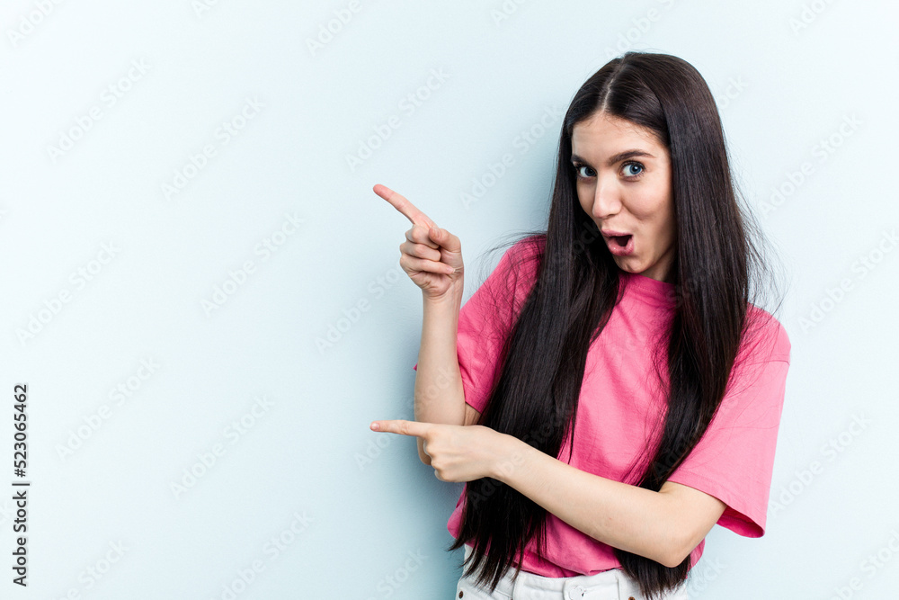 Young caucasian woman isolated on blue background pointing with forefingers to a copy space, expressing excitement and desire. Young caucasian woman isolated on blue background pointing with forefingers to a copy space, expressing excitement and desire.