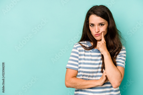 Young caucasian woman isolated on blue background looking sideways with doubtful and skeptical expression. © Asier