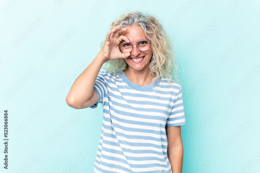 Middle age caucasian woman isolated on blue background excited keeping ok gesture on eye. Middle age caucasian woman isolated on blue background excited keeping ok gesture on eye.