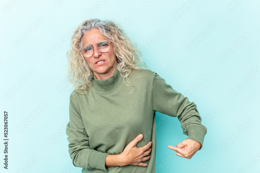 Middle age caucasian woman isolated on blue background having a liver pain, stomach ache. Middle age caucasian woman isolated on blue background having a liver pain, stomach ache.