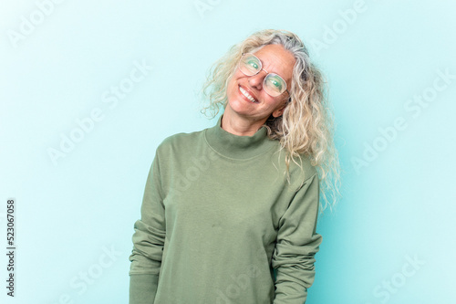 Middle age caucasian woman isolated on blue background relaxed and happy laughing, neck stretched showing teeth.