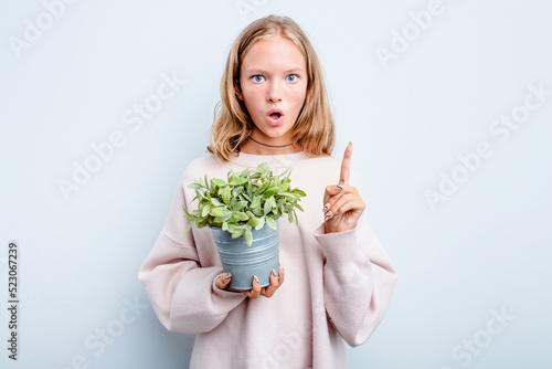 Caucasian teen girl holding a plant isolated on blue background having some great idea, concept of creativity.