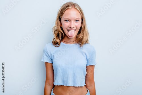 Caucasian teen girl isolated on blue background funny and friendly sticking out tongue. photo