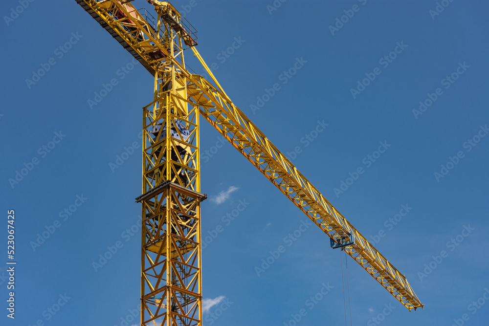 Close up perspective shot to a yellow construction crane arm against clear blue sky