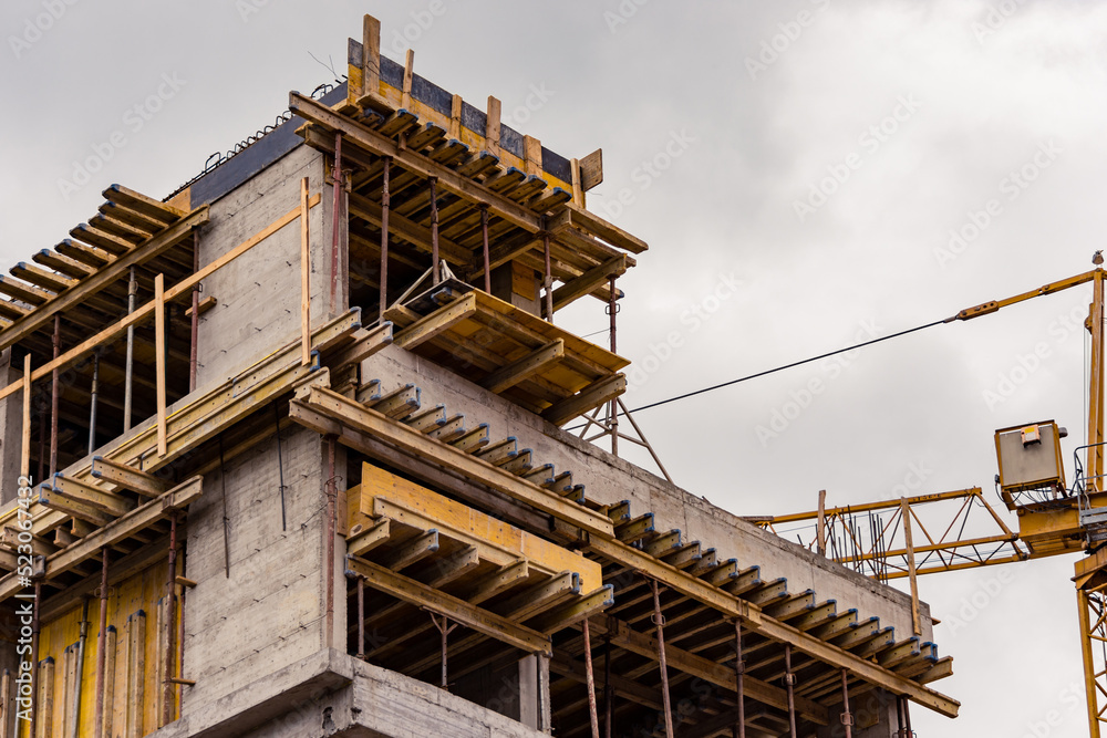 Fototapeta premium Building construction site next to a crane against a cloudy sky