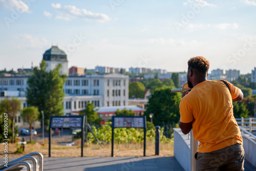 The guy in the orange T-shirt is looking through a telescope. View from the back. Observation deck in Zielona Góra, Poland.