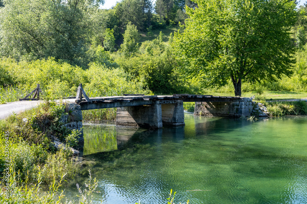 Old, wooden bridge passing over beautiful Korana river flowing directly from Plitvice national park lakes, Croatia
