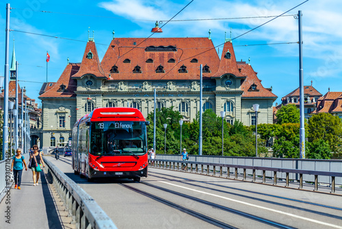 BERN, SWITZERLAND - August 2nd 2022: The red bus on the Kirchenfeld Bridge over the Aare River. Public transport.