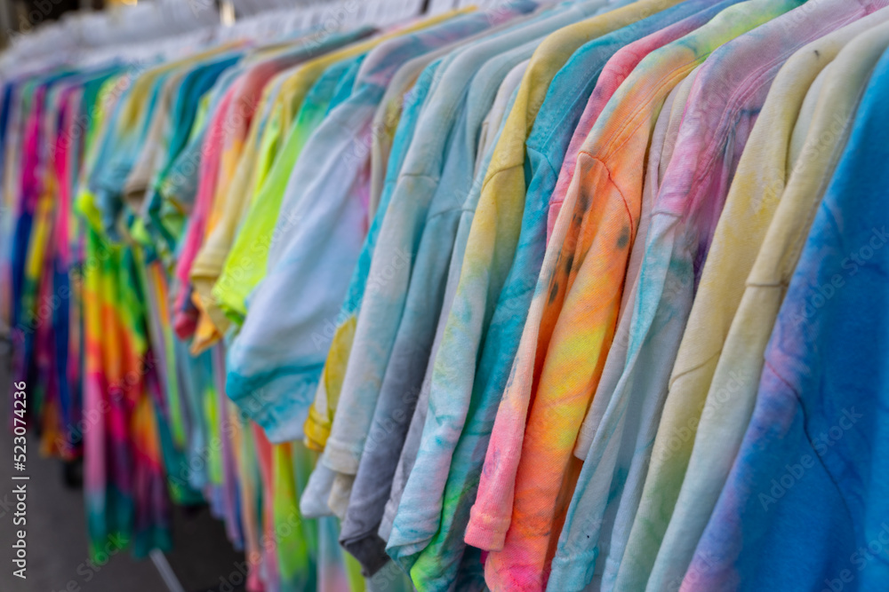 Tie dye shirts for sale at a gift shop, hanging on a rack