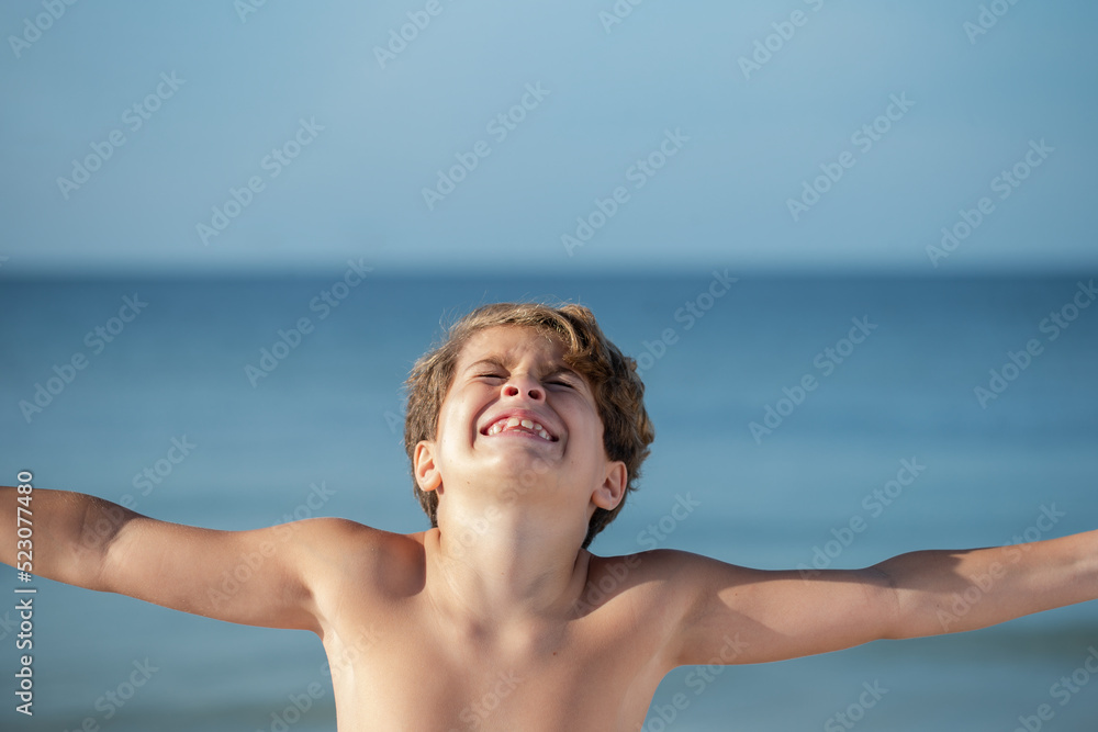 Young boy very happy with arms out and big smile on a beach in Florida Young boy very happy with arms out and big smile on a beach in Florida