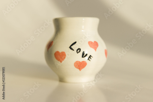 small white pot with hearts and the inscription Love. ceramic product. author's work