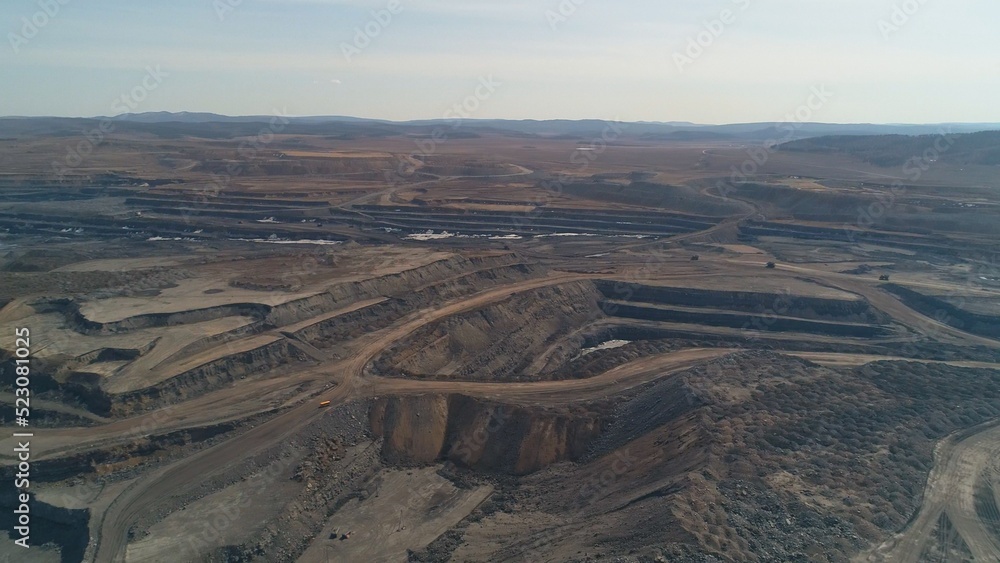 Deep quarry with working equipment. Mining machines. Excavator, dump truck, loader. Copter view