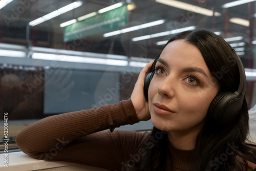 Young woman in headphones listening to music in a subway car. travels underground in europe.