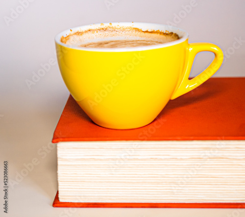 cup of coffee sitting on top of book with orange cover