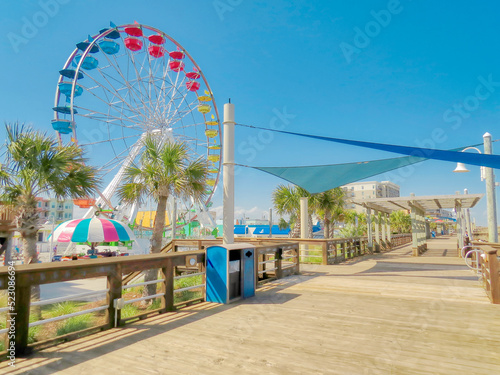 A beach view of a Ferris wheel by a wooden boardwalk at Carolina Beach, North Carolina in pastel colors.