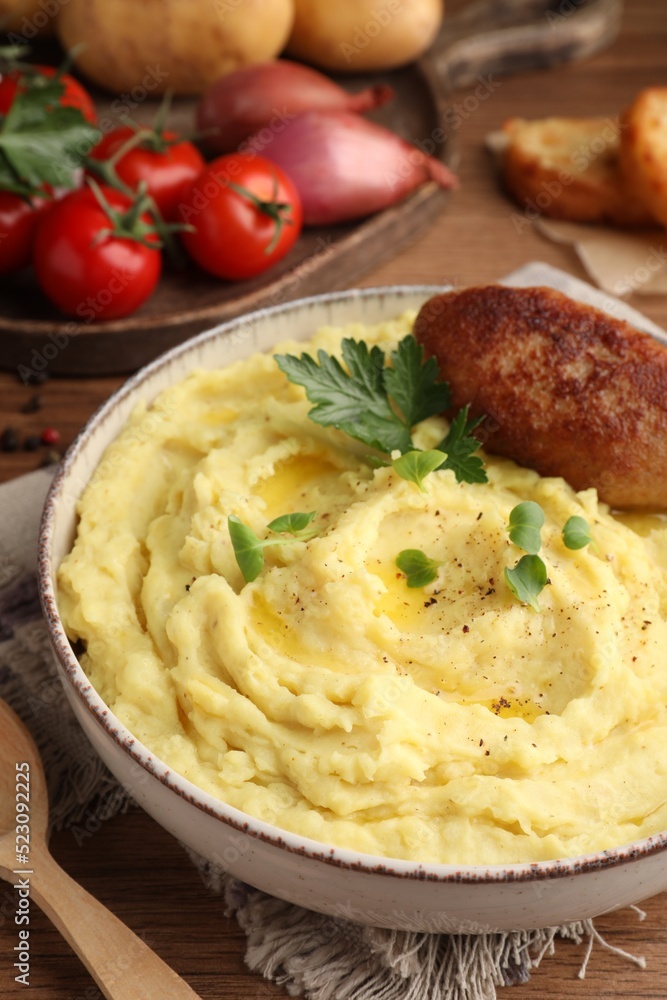 Bowl of tasty mashed potatoes with parsley, black pepper and cutlet served on wooden table, closeup Bowl of tasty mashed potatoes with parsley, black pepper and cutlet served on wooden table, closeup