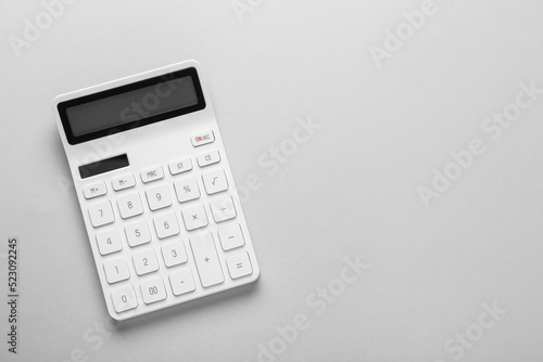 White calculator on light background, top view. Space for text photo