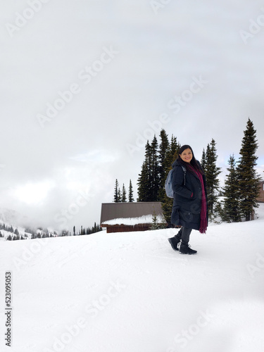 Latin adult woman with black jacket and gray backpack hiking in the snowy mountain very happy, free, full, positive, enjoys life and sports