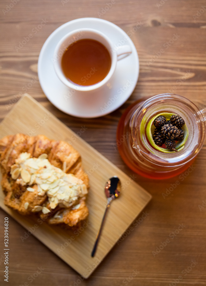 Breakfast in the cafe. juniper tea with lime served in a glass chemex, a cup of hot tea and a croissant with almonds. Breakfast in the cafe. juniper tea with lime served in a glass chemex, a cup of hot tea and a croissant with almonds.