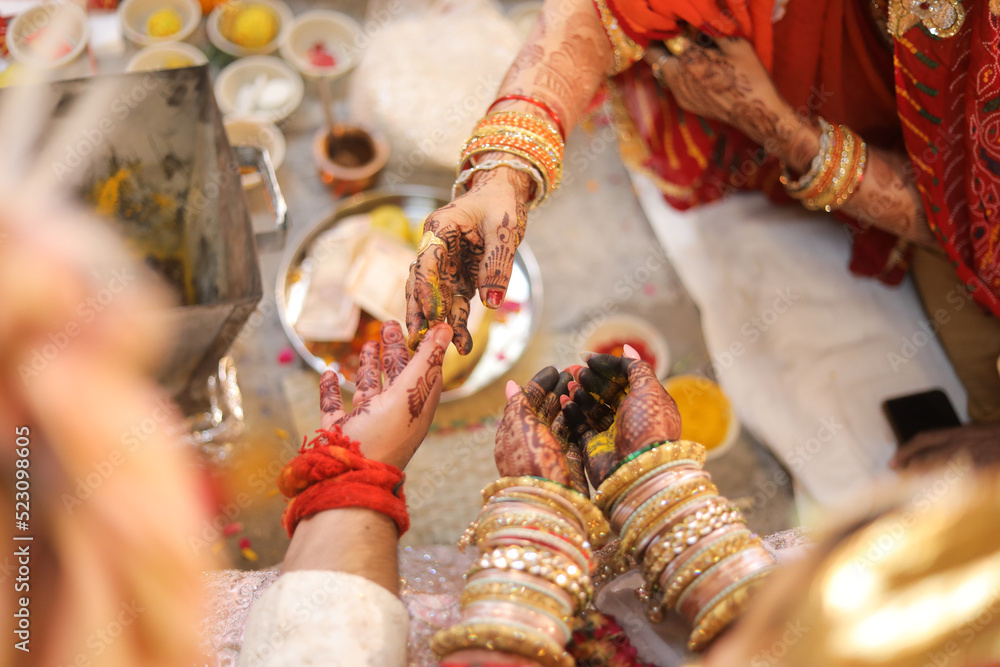 Obraz premium Mother putting turmeric on the hands of bride and groom during Indian wedding 