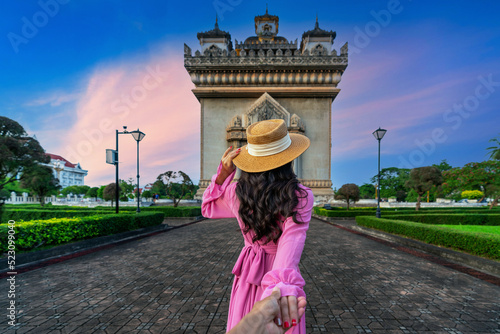 Women tourists holding man's hand and leading him to Patuxai in Vientiane, Laos. photo