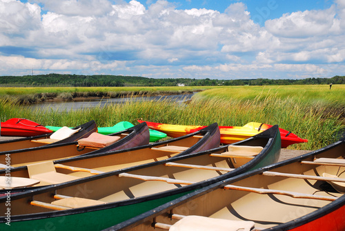 Canoes are parked on a dock near a brook of a salt marsh in a nature preserve photo