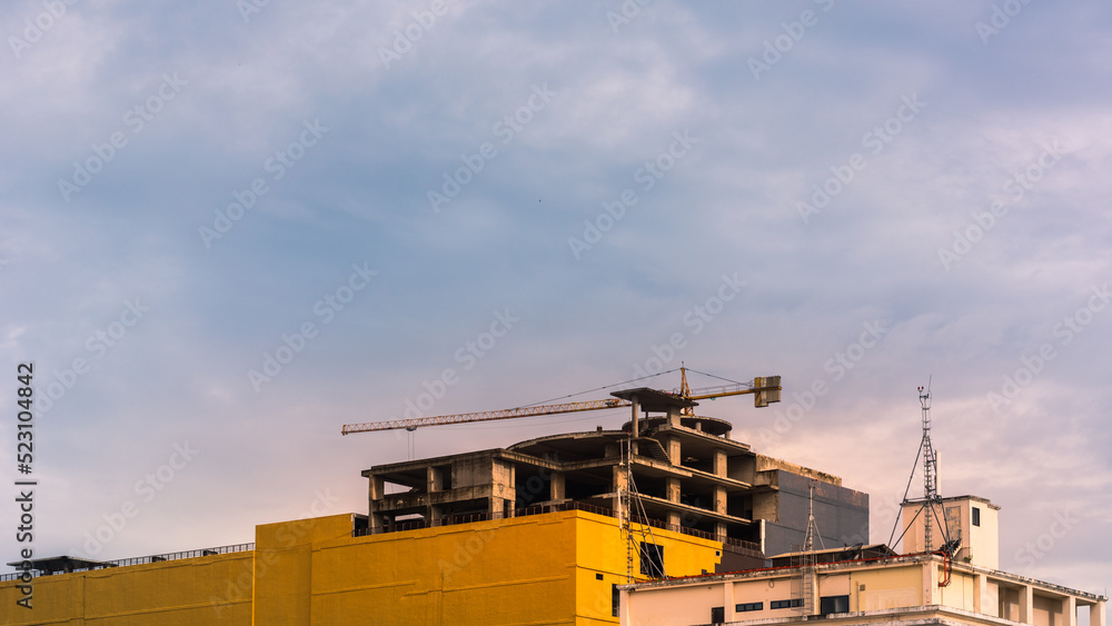 Construction site with tower crane on blue sky with clouds background.