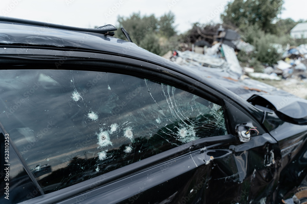 Shot car during the war in Ukraine. A car of civilians with shrapnel holes from explosions. Traces of shots on the body. The car was damaged after the shelling. Ukraine, Bucha - July 15, 2022 Shot car during the war in Ukraine. A car of civilians with shrapnel holes from explosions. Traces of shots on the body. The car was damaged after the shelling. Ukraine, Bucha - July 15, 2022