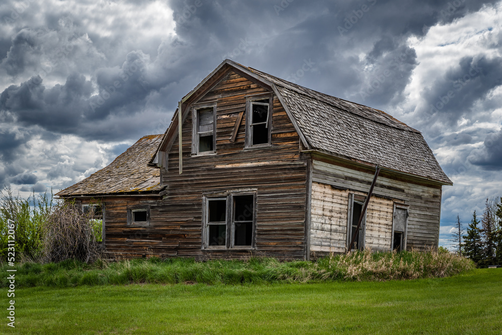 Stormy skies over a stately old, abandoned home on the prairies of Saskatchewan 
