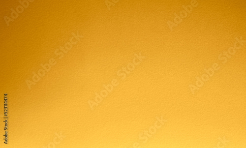 Gold wall texture background. Yellow shiny gold foil paint on wall surface with light reflection, vibrant golden luxury wallpaper