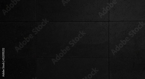 close up dark black modern building stone wall tile, porous stone, granite texture background. exterior rusty and grungy stone wall use as background. matt wall tile with dry process installation.