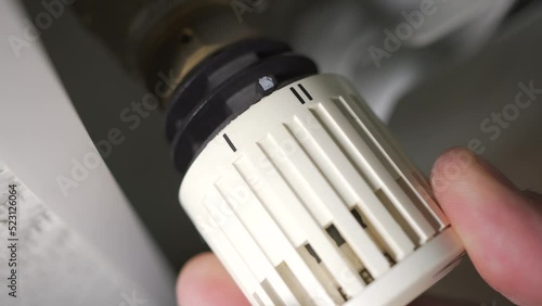 Man adjusts the temperature of the battery. Thermostat for fixing and limiting the temperature setting in heating radiators.