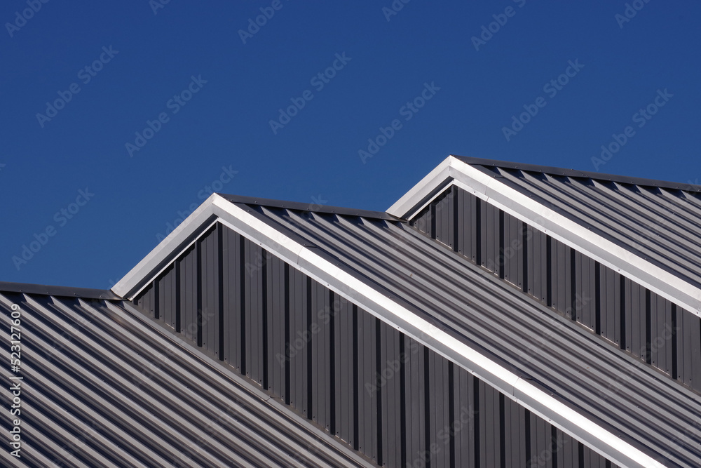 Partial view of cascading warehouse rooftops under blue sky Partial view of cascading warehouse rooftops under blue sky