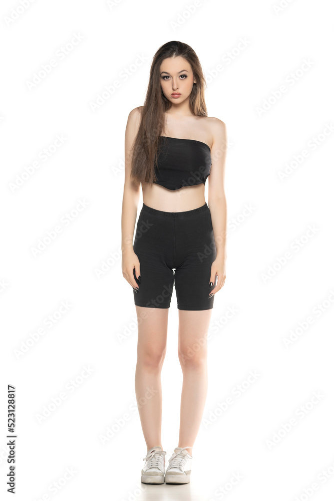 Young woman in black shorts and top posing in the studio on white. Young woman in black shorts and top posing in the studio on white.