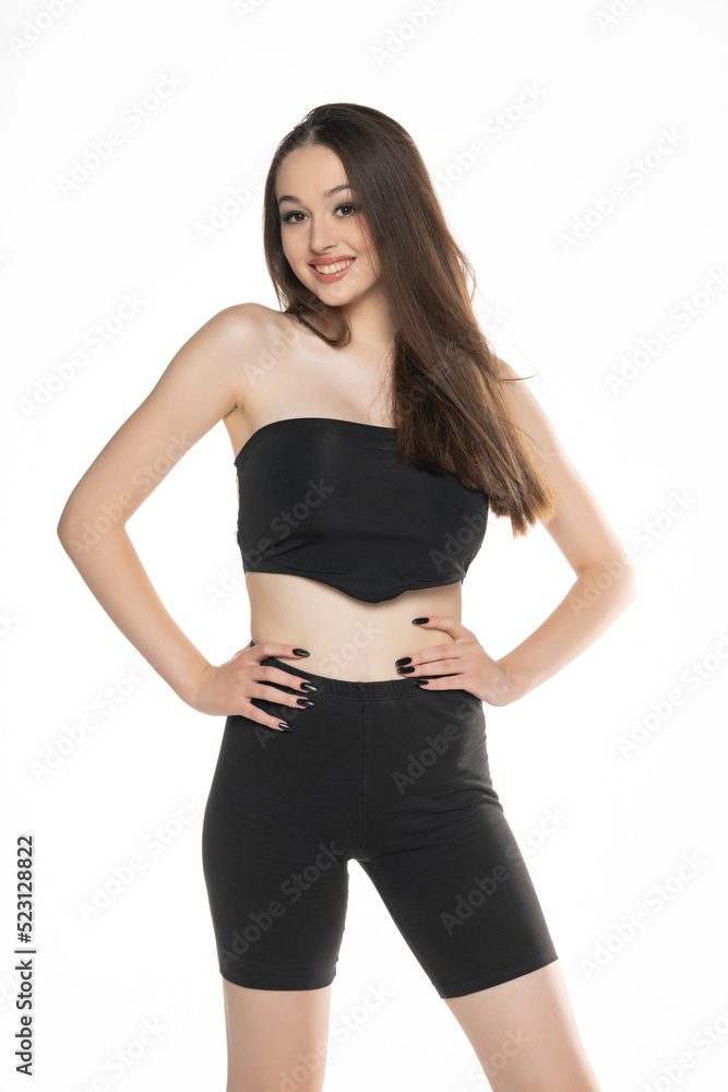 Young woman in black shorts and top posing in the studio on white Young woman in black shorts and top posing in the studio on white